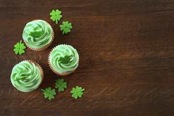 Tasty cupcakes with clover on wooden background. Saint Patrics Day concept