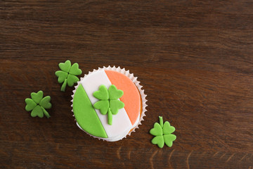 Tasty cupcake with clover on wooden background. Saint Patrics Day concept