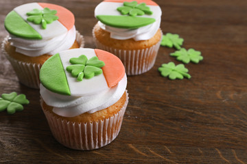 Tasty cupcakes with clover on wooden background. Saint Patrics Day concept
