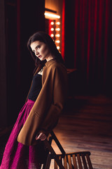 woman in skirt and jacket sitting on chair indoor shot