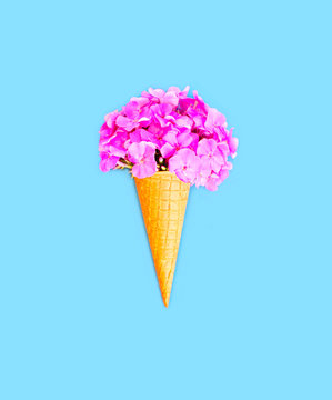 Ice cream cone with flowers over blue background top view