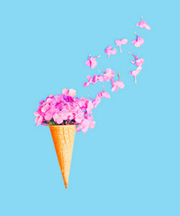 Ice cream cone with petals flowers over blue background top view