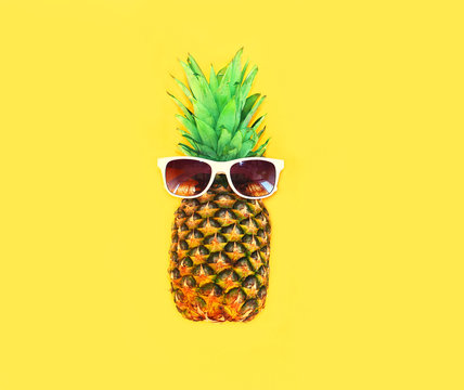 Pineapple with sunglasses on yellow background colorful ananas