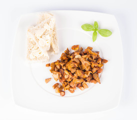 Sauteed chanterelle with garlic and some white bread on a plate decorated with basil