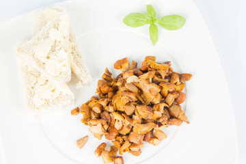 Sauteed chanterelle with garlic and some white bread on a plate decorated with basil