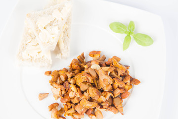 Sauteed chanterelle with garlic and some white bread on a plate decorated with basil