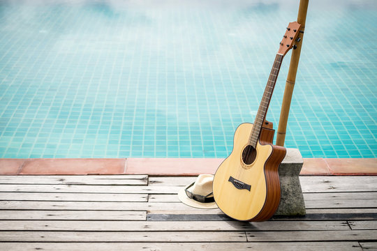 Acoustic guitar leaning on swiming pool.