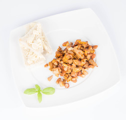 Sauteed chanterelle with garlic and some white bread on a plate decorated with basil