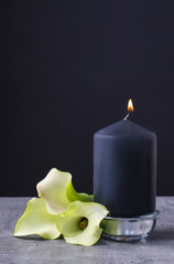 Black candle and calla flowers (Zantedeschia)