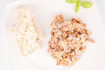 Sauteed chanterelle with cream and garlic and some white bread on a plate decorated with basil