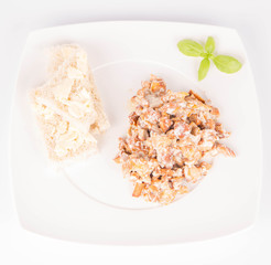 Sauteed chanterelle with cream and garlic and some white bread on a plate decorated with basil