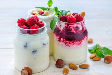 Yogurt with raspberries and nuts in jars.