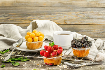 beautiful cupcakes with berries on wooden background