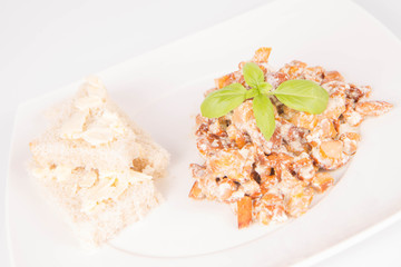 Sauteed chanterelle with cream and garlic and some white bread on a plate decorated with basil