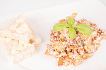 Sauteed chanterelle with cream and garlic and some white bread on a plate decorated with basil