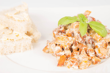 Sauteed chanterelle with cream and garlic and some white bread on a plate decorated with basil