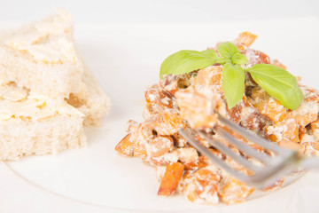 Sauteed chanterelle with cream and garlic and some white bread on a plate decorated with basil
