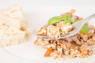 Sauteed chanterelle with cream and garlic and some white bread on a plate decorated with basil