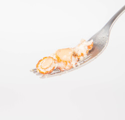 Sauteed chanterelle with cream and garlic on a fork on white background
