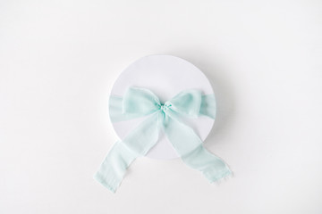 white gift cardboard box with blue bow on white background. flat lat, top view