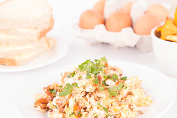 Scrambled eggs with chanterelle and parsley on a white background
