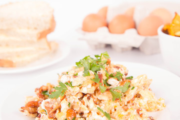 Scrambled eggs with chanterelle and parsley with some white bread on a white background