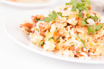 Scrambled eggs with chanterelle and parsley with some white bread on a white background