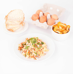 Scrambled eggs with chanterelle and parsley with some white bread on a white background