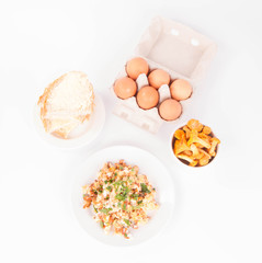 Scrambled eggs with chanterelle and parsley with some white bread on a white background