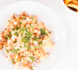 Scrambled eggs with chanterelle and parsley on a white background