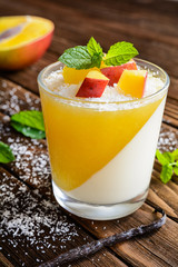 Coconut panna cotta dessert with mango jelly in a glass jar