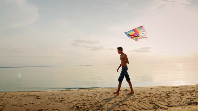 Teen playing with a kite near the sea in the beautiful sky