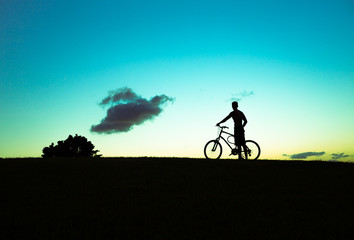 Obraz premium Man on a bicycle stoping to enjoy the sunset. 