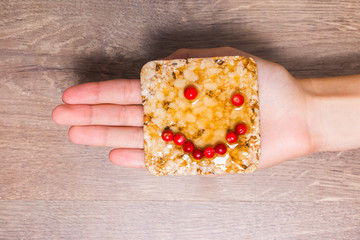 Female hand holding a sandwich of crispy bread, honey and cranbe