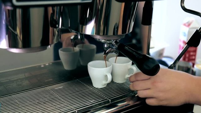 The cappuccino is poured into two mugs from the coffee machine