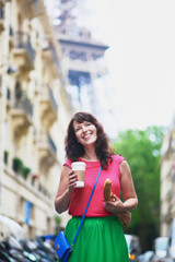 French woman walking with coffee to go and baguette on a street of Paris