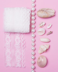 Sea shells, pearls and lace on a pink background