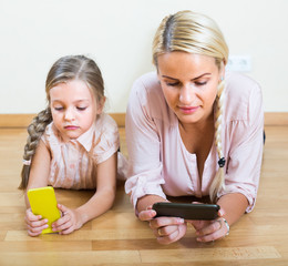 Woman and daughter with smartphones.