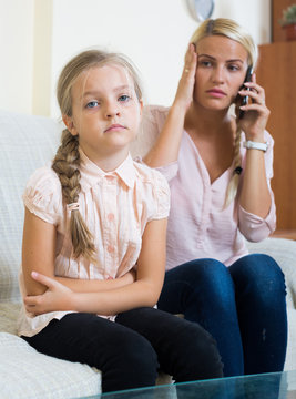 Worried mother calling doctor for daughter with abdominal pains