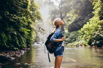 Relaxed female hiker standing by the stream