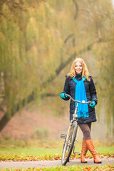 Fototapeta na wymiar Happy active woman with bike in autumn park.