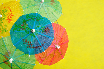 Open cocktail umbrellas displayed on a yellow background