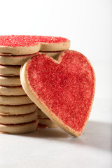 stacked Valentine cookies and a big heart on marble board, isolated on white background, close up, vertical