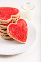homemade, heart shaped cookies in a white plate and milk, Valentine's Day, isolated on white, close up, macro, selective focus, vertical