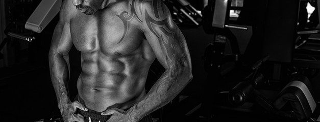 Fototapeta na wymiar Athlete muscular brutal bodybuilder emotional posing in the gym