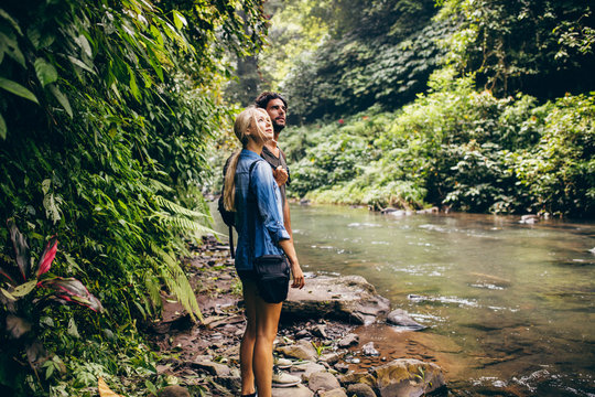 Couple standing by stream in woods