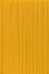 golden color, spaghetti pasta as background, close-up, top view, vertical