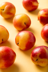delicious, sweet, organic plums in red and yellow, isolated on a yellow craft paper background, close up, vertical