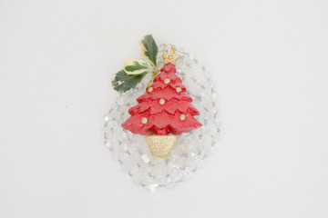 Red Christmas tree ornament on a light background with natural holly