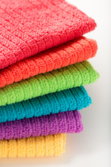 pile of bathroom towels in rainbow colors, isolated over a white background, close up, vertical